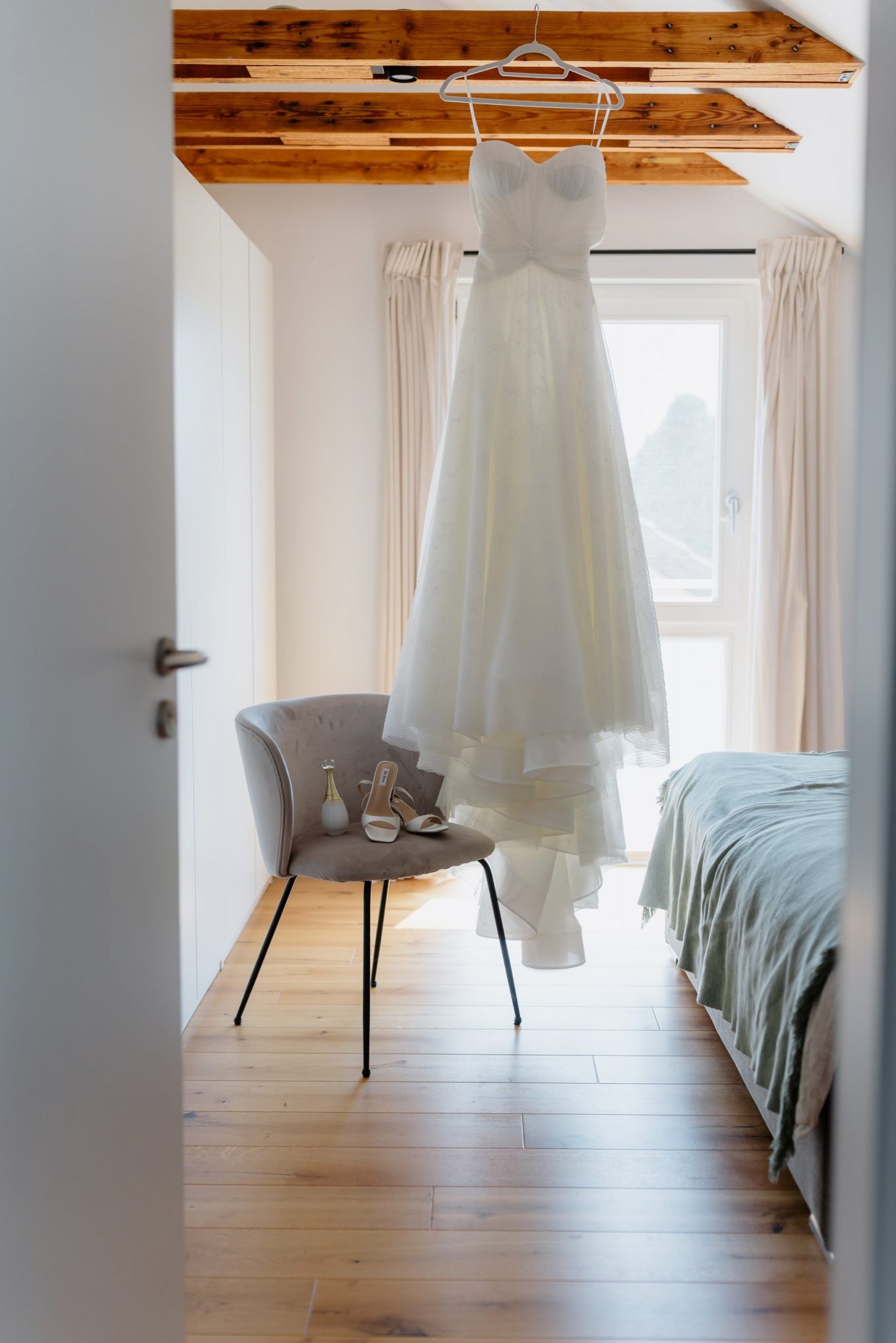 Brautkleid hängt am Fenster vor dem Getting Ready