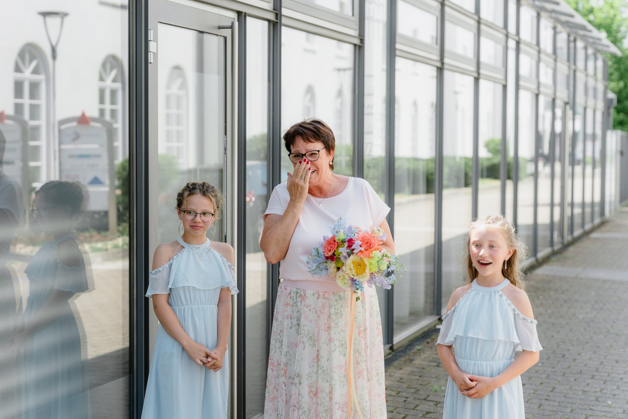 Brautmama hält sich gerührt die Hand vor den Mund beim First Look