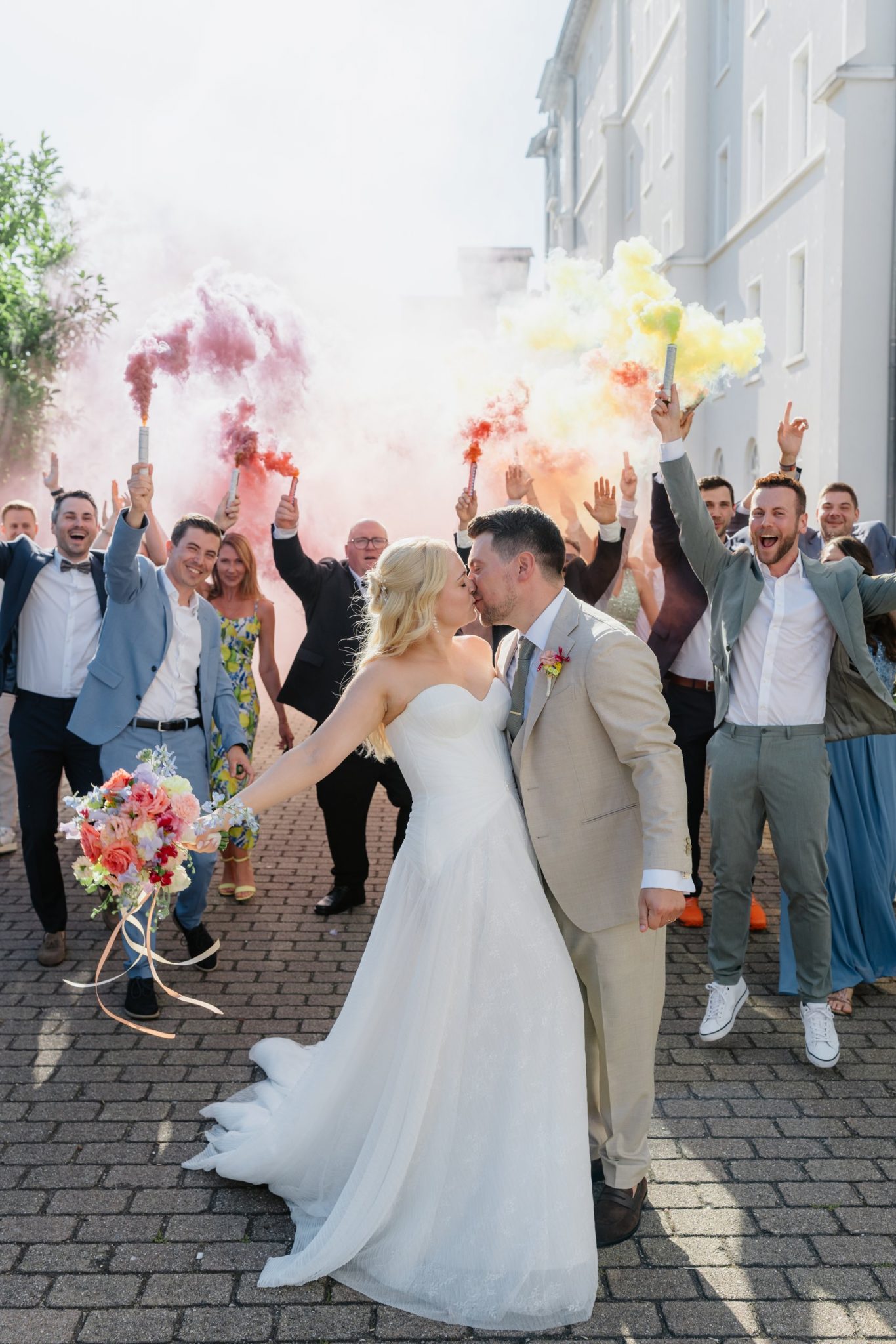 Brautpaar küsst sich unter bunten Rauchschwaden der Smokebombs