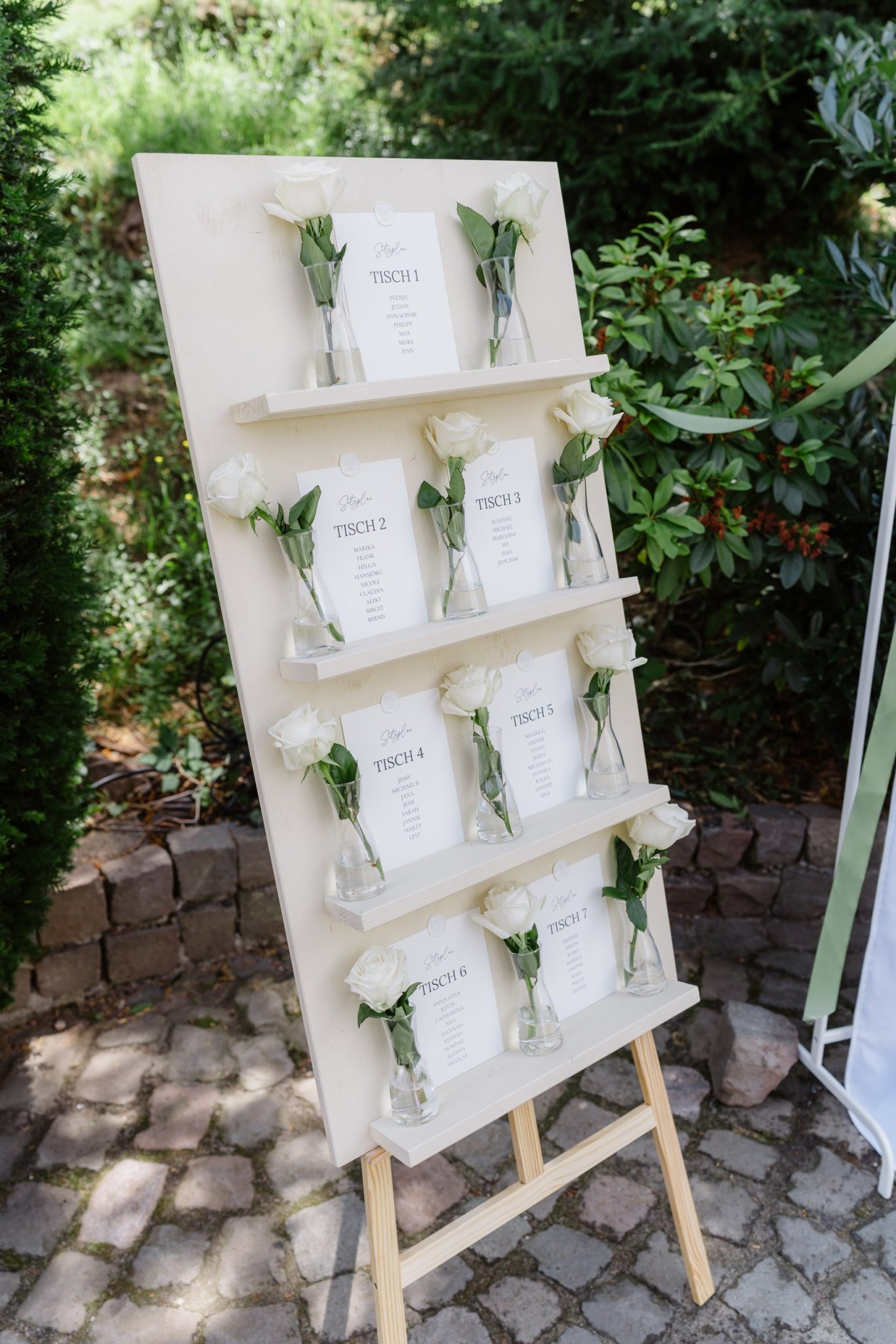 Sitzplan der Hochzeit auf einer weißen Staffelei im Garten des Kitchen & Soul