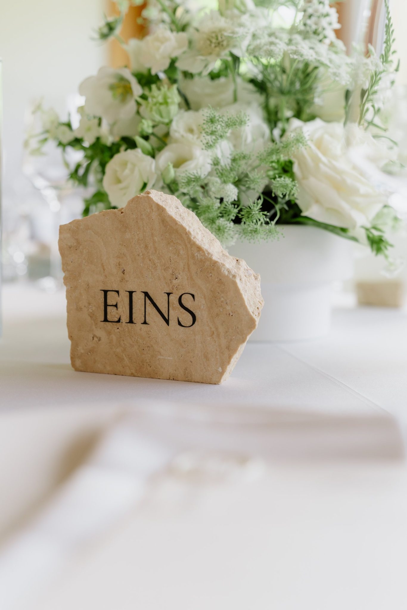 Tischnummer aus Stein neben weißen Blumen