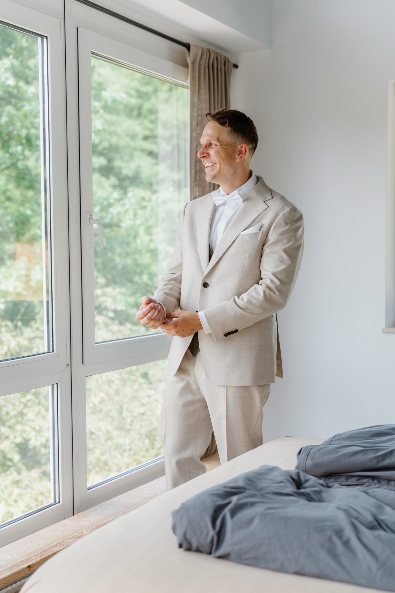 Julian im hellen Anzug von Suitsupply am Fenster