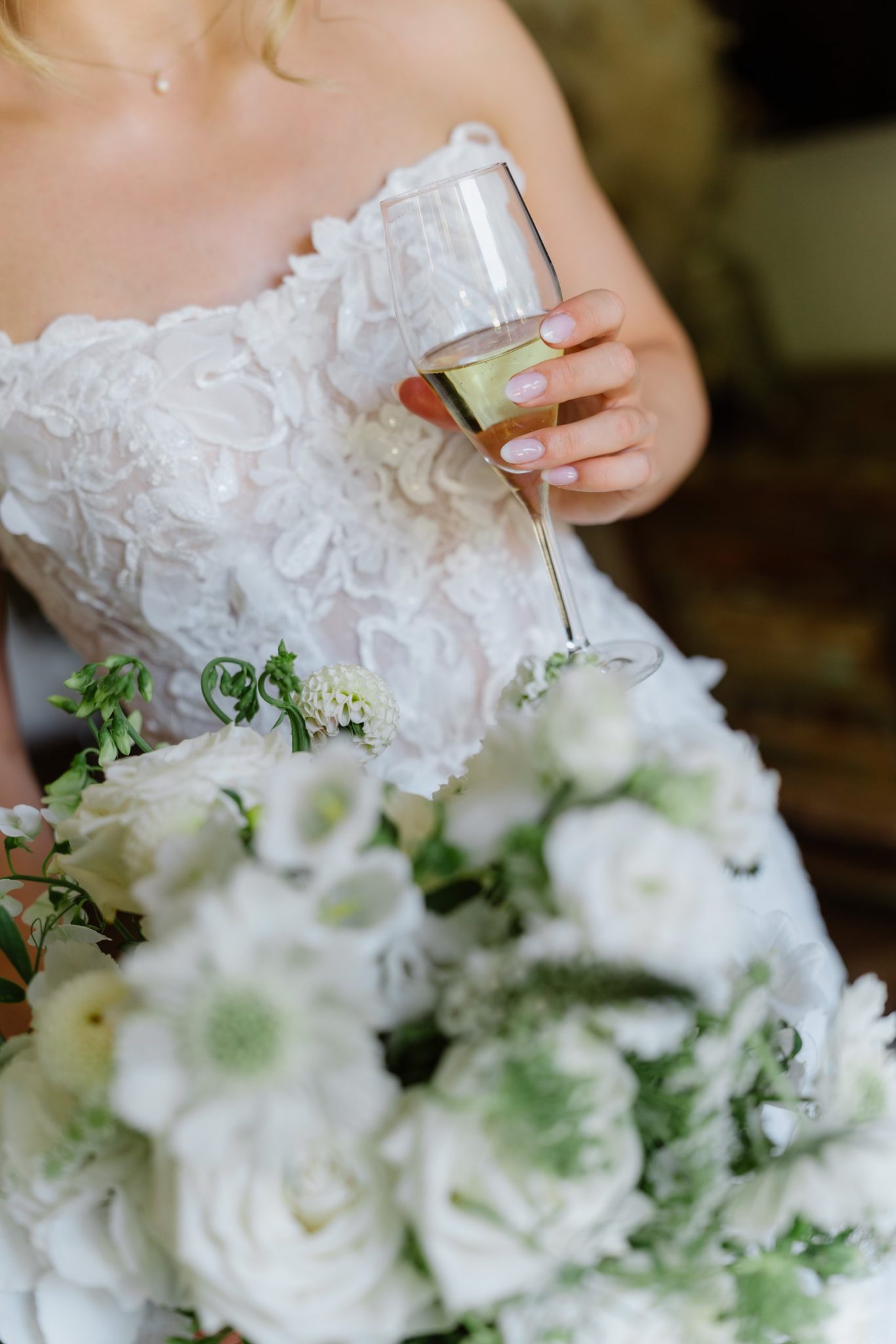Svenja hält Sektglas und Brautstrauß aus weißen Rosen