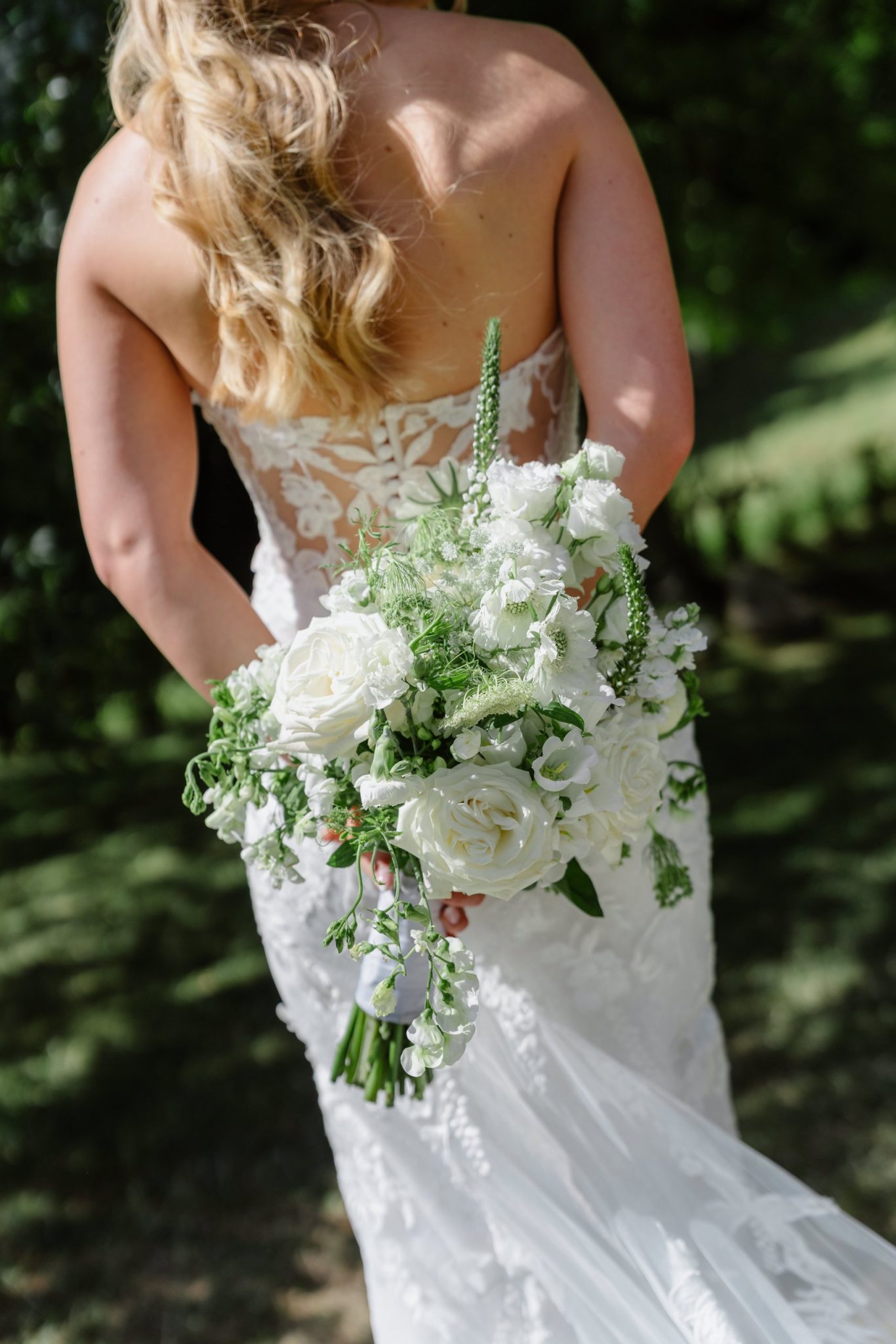 Rückenausschnitt des Brautkleids vom Hochzeitshaus Boos mit Brautstrauß
